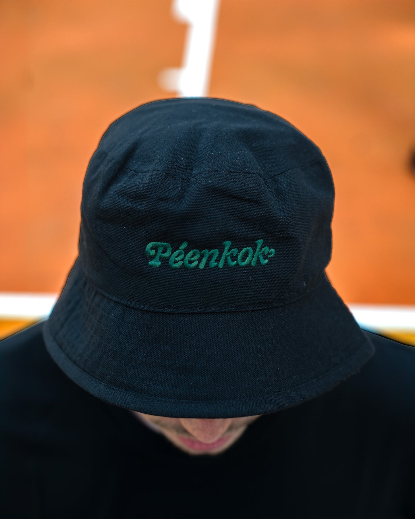 PÉENKOK' | ORGANIC COTTON SUSTAINABLE FASHION BLACK BUCKET HAT WITH ORGANIC EMBROIDERY ON THE FRONT WORN BY A MAN