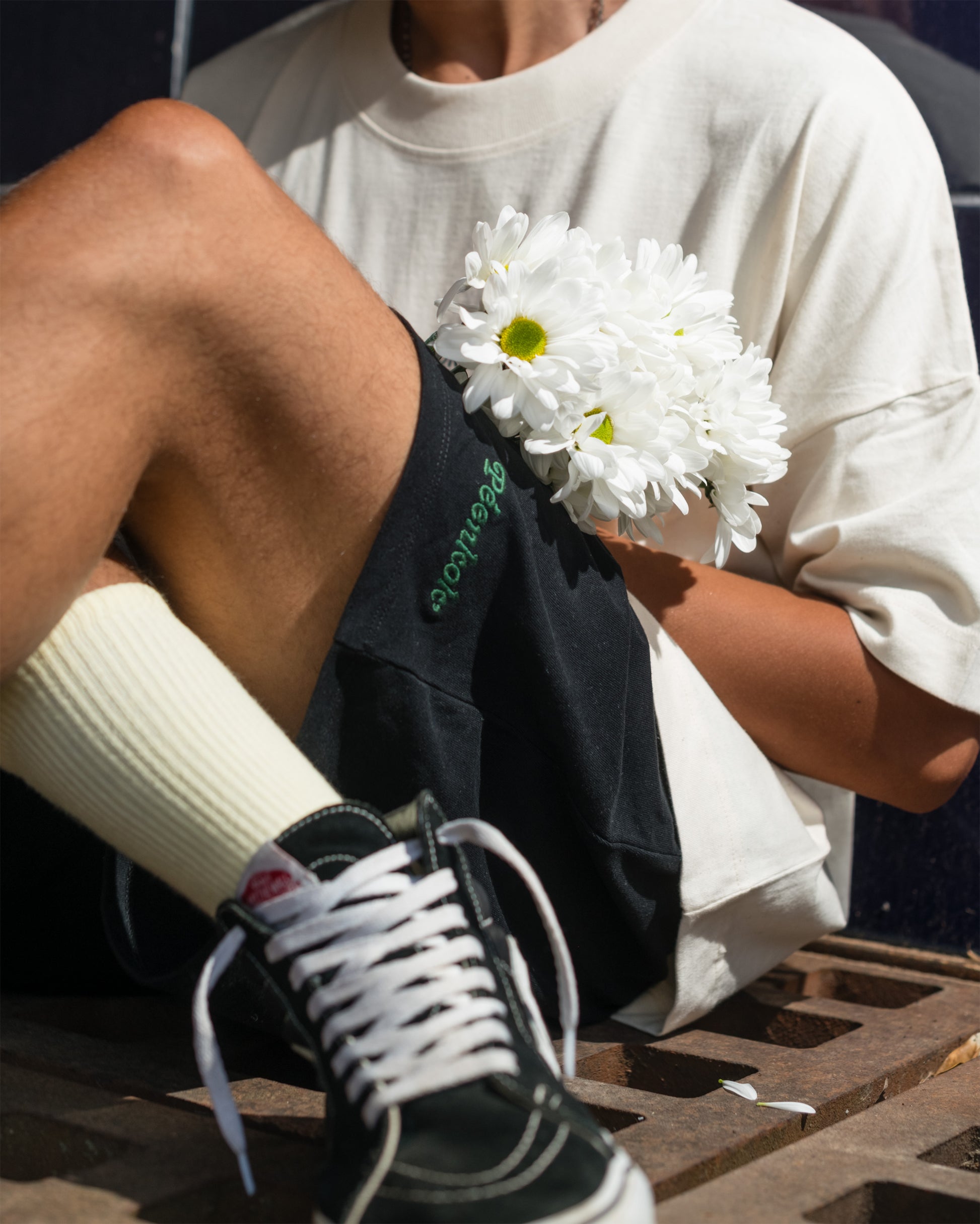 PÉENKOK' | ORGANIC COTTON BLACK EMBROIDERED SHORT WORN BY MAN THAT HAS A BOUQUET OF FLOWERS